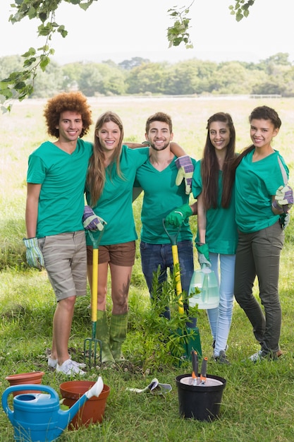 Groep vrijwilligers in groene t-shirts plant bomen in park, community engagement